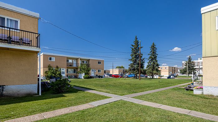 Charming apartment complex with vibrant green lawns and inviting outdoor seating, perfect for relaxation and enjoying sunny days.