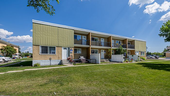 Charming two-story apartment building with lush green lawns and sunny balconies, set in a tranquil neighborhood.