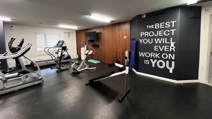 Inviting fitness room featuring modern exercise equipment and motivational wall quote for an inspiring workout experience.