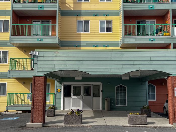 Charming apartment complex with vibrant yellow and green exterior, featuring spacious balconies and welcoming entrance.