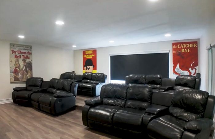 Cozy home theater room with plush black leather recliners and stylish literary-themed wall art.