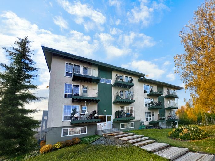 Charming residential building surrounded by lush greenery and vibrant autumn trees, featuring multiple balconies perfect for enjoying the scenic views.