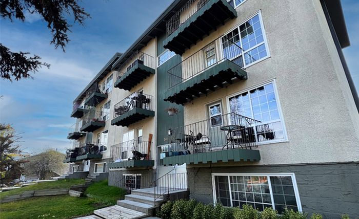 Charming apartment building with multiple balconies, large windows, and inviting greenery, perfect for enjoying the outdoors.