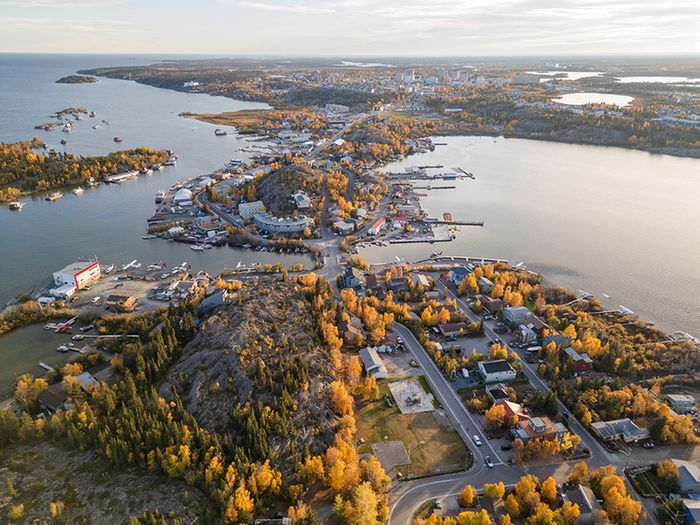 Breathtaking aerial view of a picturesque coastal town surrounded by shimmering waters and vibrant autumn foliage.