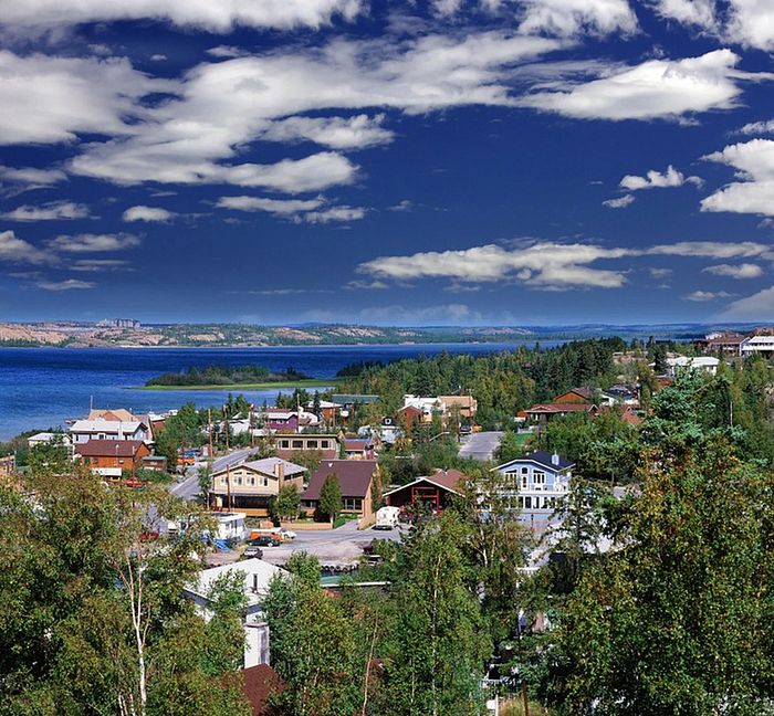 Charming lakeside community with scenic views, nestled among lush greenery under a vibrant blue sky.