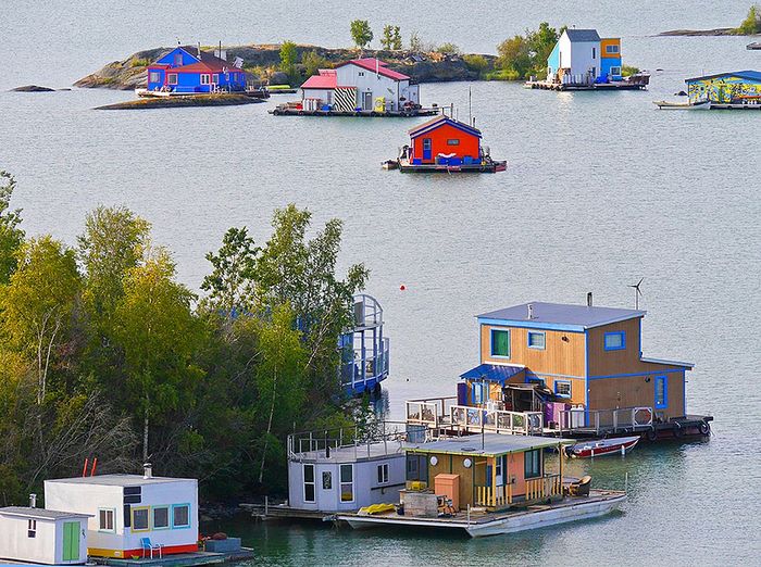 Charming floating homes with vibrant colors and picturesque surroundings on a serene lake, offering a unique waterfront lifestyle.