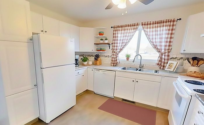 Bright and welcoming kitchen with modern white cabinetry, chic tiled backsplash, and a window with checkered curtains. Includes essential appliances and ample counter space, perfect for culinary enthusiasts.