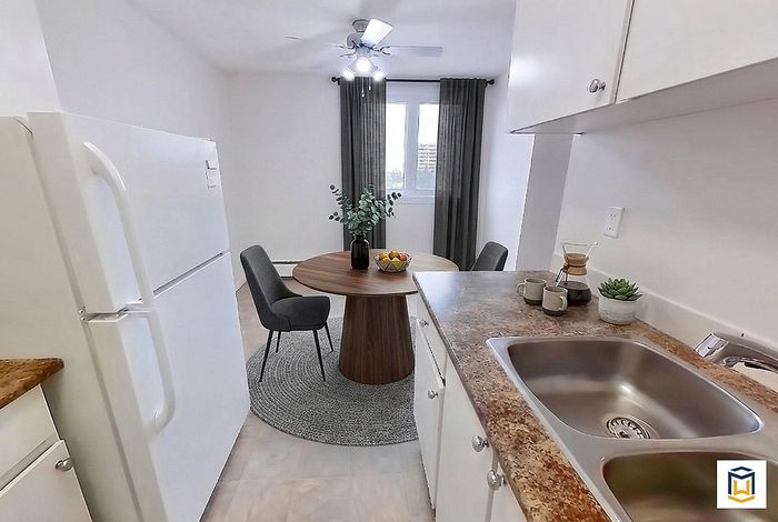 Charming kitchen with a cozy dining nook, featuring modern appliances, a round wooden table, and elegant chairs next to a bright window.