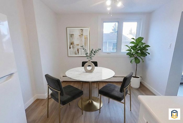 Chic dining area with a modern touch featuring a round marble table, stylish grey chairs, and elegant greenery under soft natural light.