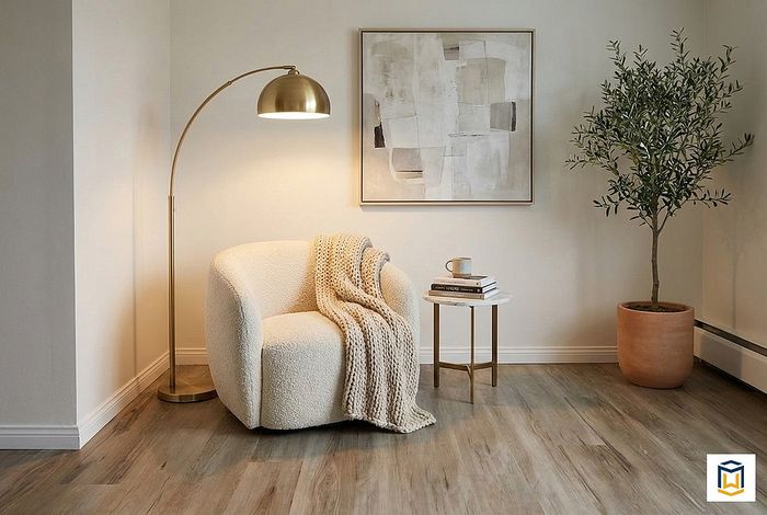 Chic reading nook with a cozy armchair, elegant floor lamp, abstract wall art, and lush potted plant for a serene ambiance.
