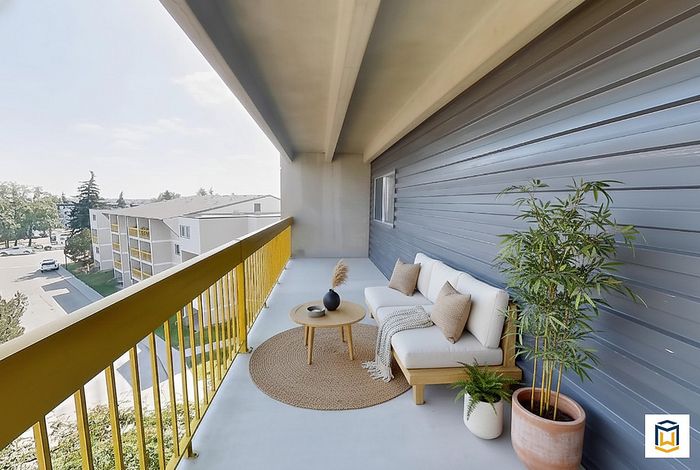Chic and inviting apartment balcony with cozy seating, potted plants, and refreshing views of the neighborhood.