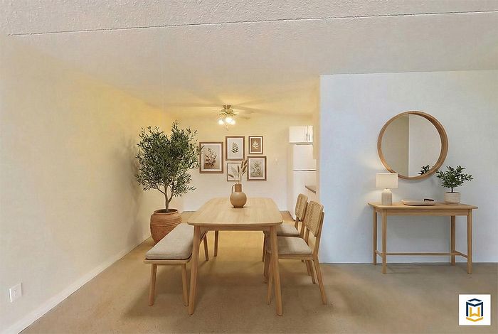Charming dining area featuring a sleek wooden table with soft cushioned seats, elegant wall art, and greenery adding a touch of nature.