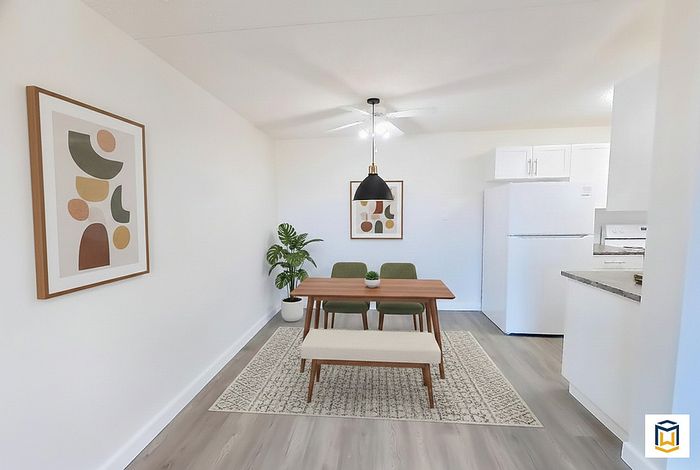 Bright dining area with modern wooden table, stylish chairs, and contemporary art, blending seamlessly into a sleek kitchen with white cabinetry.