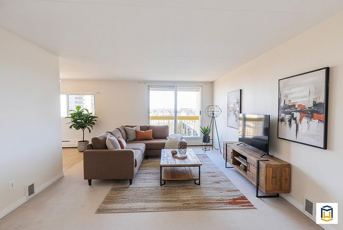 Bright and modern living room with a cozy sectional sofa, stylish decor, and floor-to-ceiling windows offering panoramic views.