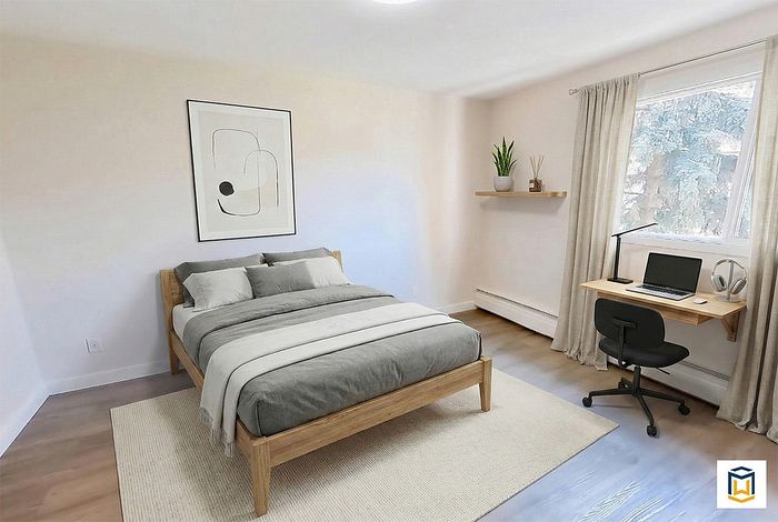 Bright and cozy bedroom featuring a comfortable bed, modern decor, and a compact work desk with a garden view.