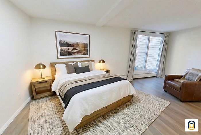Inviting bedroom with a plush bed, elegant artwork, and warm lighting, creating a cozy atmosphere with modern furnishings.