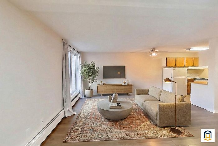 Inviting living room with stylish beige couch, elegant rug, and open kitchen area, perfect for comfortable living.