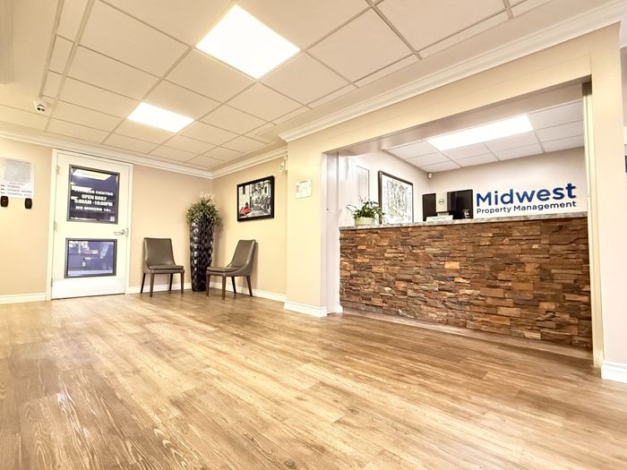 Inviting lobby of Midwest Property Management featuring a stylish stone accent wall, modern seating, and warm wooden flooring.
