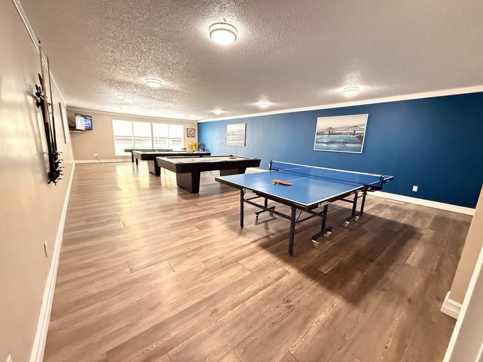 Inviting recreation room with ping pong and billiards tables, accented by sleek design and ample natural light.