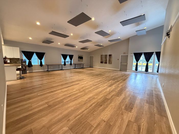 Expansive room with elegant wood flooring, modern ceiling fixtures, and abundant natural light from large windows.
