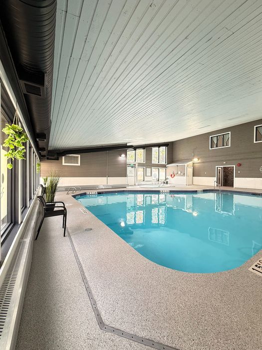 Inviting indoor pool area with large windows, modern decor, and natural light creating a relaxing atmosphere.