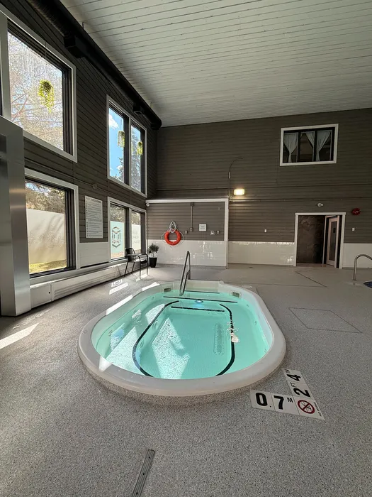 Inviting indoor pool area with large windows, featuring a modern jacuzzi and plenty of natural light.