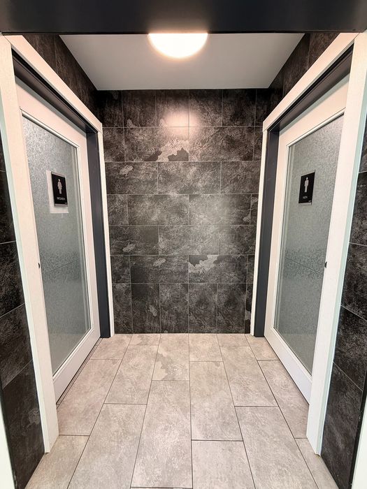 Modern restroom entry with sleek tile walls and frosted door panels, creating a sophisticated and welcoming atmosphere.