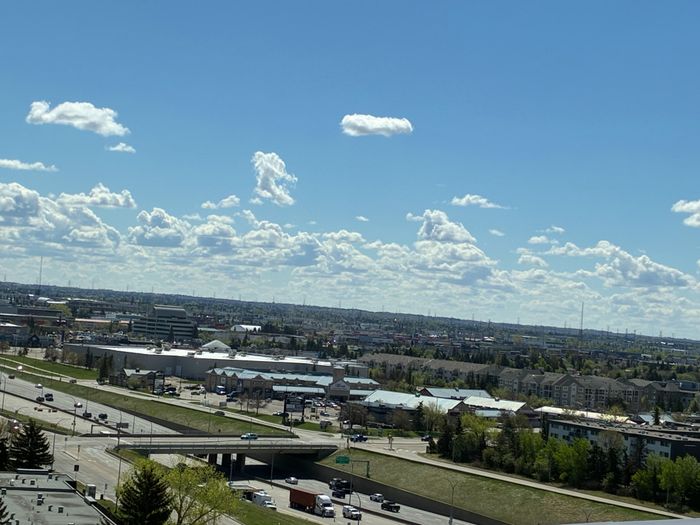 Breathtaking cityscape view from an apartment, showcasing a vibrant skyline under a clear blue sky with fluffy clouds.