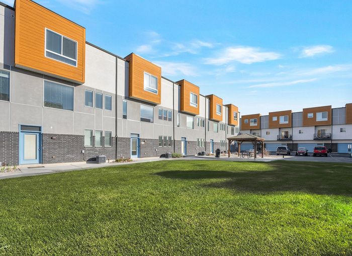 Charming residential building surrounded by lush greenery and vibrant autumn trees, featuring multiple balconies perfect for enjoying the scenic views.