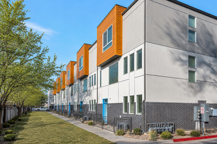 Charming residential building surrounded by lush greenery and vibrant autumn trees, featuring multiple balconies perfect for enjoying the scenic views.
