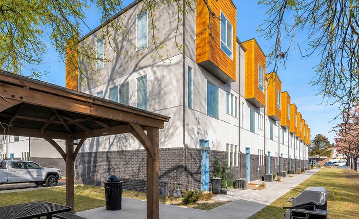 Charming residential building surrounded by lush greenery and vibrant autumn trees, featuring multiple balconies perfect for enjoying the scenic views.