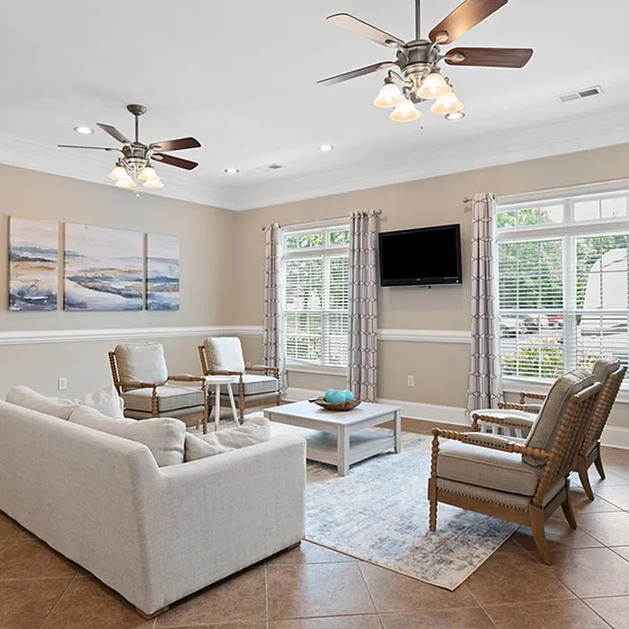 Bright and stylish living room with modern furnishings, large windows, and ceiling fans.