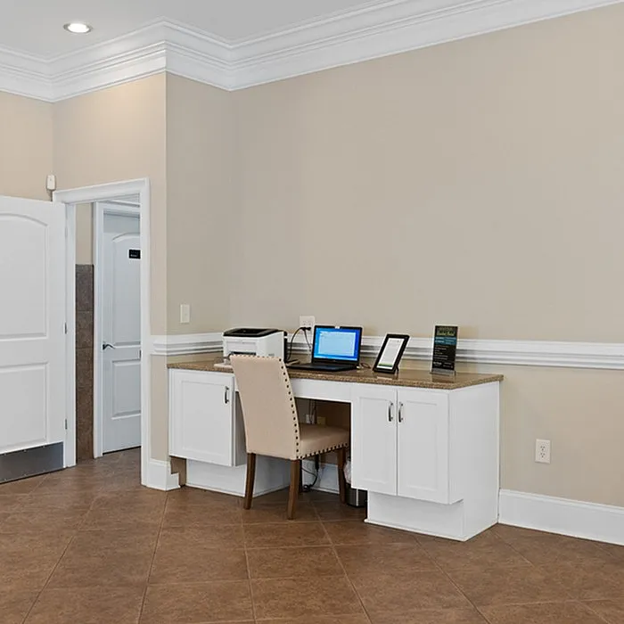 Stylish home office corner featuring a built-in desk with a laptop and printer, accented by chic white cabinetry.