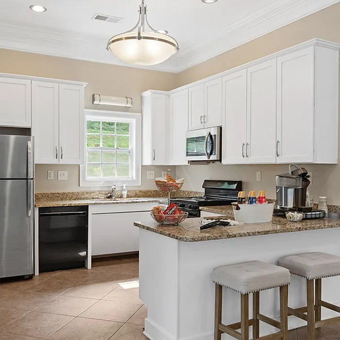 Bright and modern kitchen with white cabinets, stainless steel appliances, and a cozy breakfast bar.
