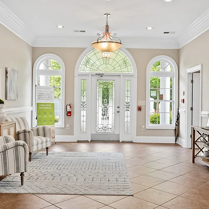 Bright and welcoming entrance with arched windows, stylish chandelier, and comfortable seating.
