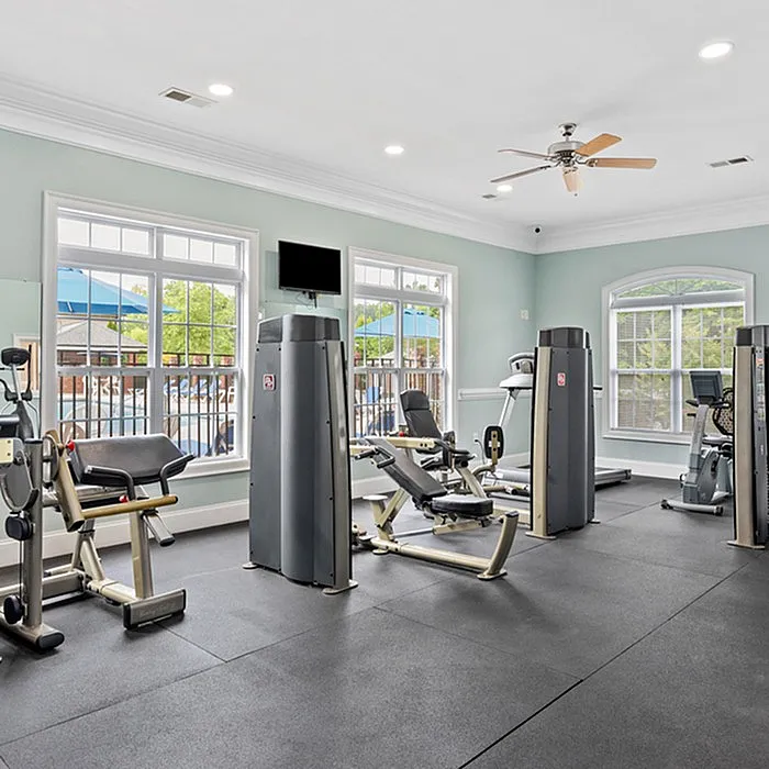 Bright fitness center with modern exercise equipment and large windows for natural light.