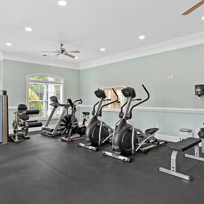 Modern gym with cardio machines and a strength training area in a bright room.