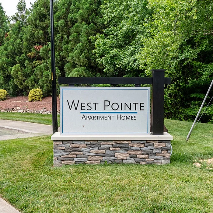 Elegant sign for West Pointe Apartment Homes surrounded by lush greenery.