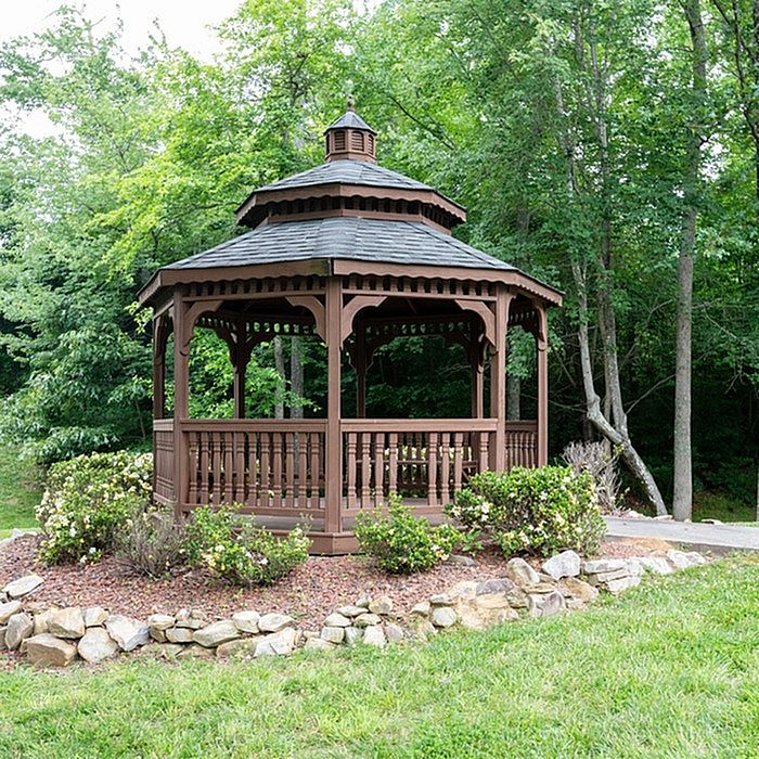 Elegant wooden gazebo surrounded by lush greenery in a tranquil garden setting.