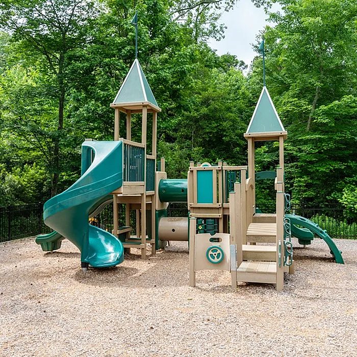 Vibrant playground with slides and climbing structures surrounded by lush greenery.