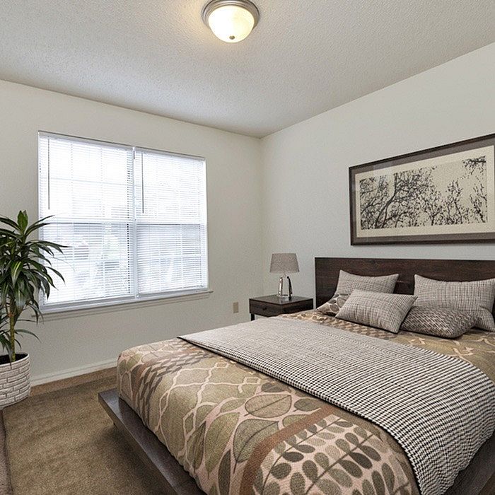 Elegant bedroom with a large window, stylish bedspread, and modern decor.