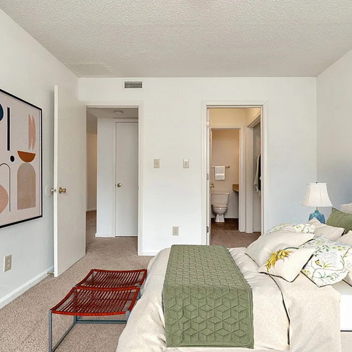 Inviting bedroom featuring a plush bed, modern art, and convenient access to an ensuite bathroom.