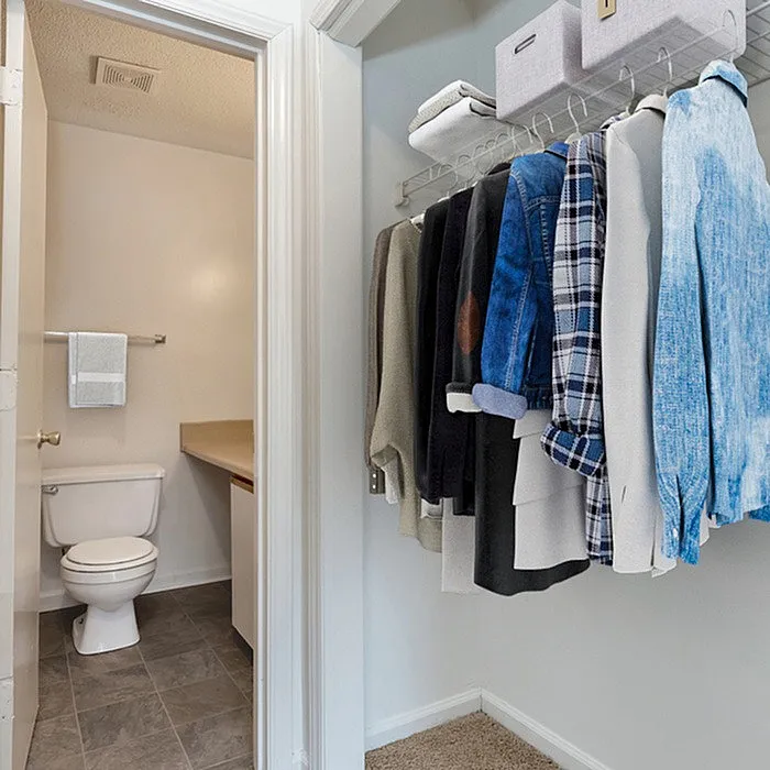 Bright hallway with organized closet and view into a modern bathroom.