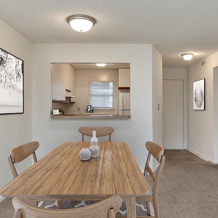 Inviting dining area with a wooden table set, adjacent to a cozy kitchen through a serving hatch.