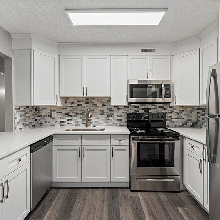 Sleek modern kitchen with stainless steel appliances, white cabinetry, and stylish backsplash.