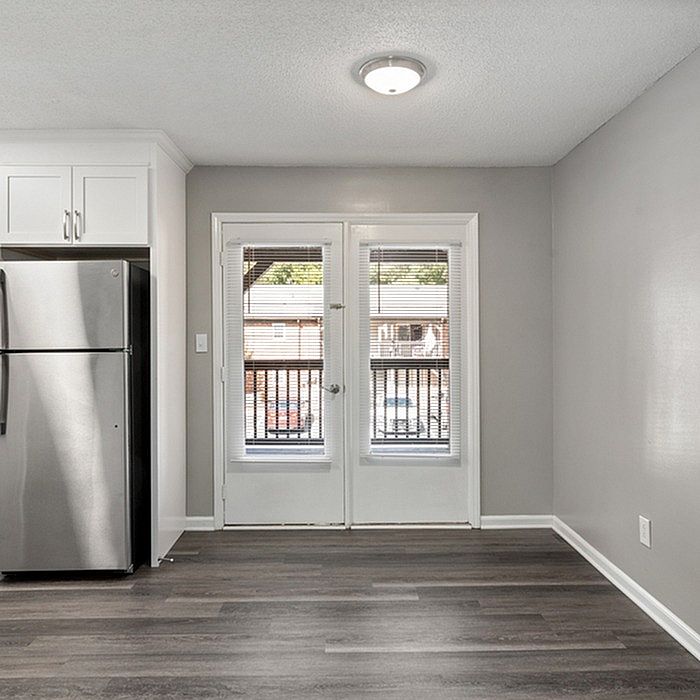 Bright kitchen area with modern stainless steel refrigerator and French doors leading to a balcony view.