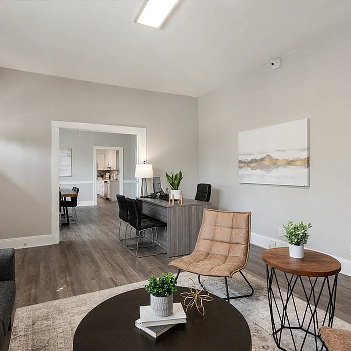 Modern living room with elegant furnishings, including a cozy chair, stylish wooden tables, and sleek workspace.