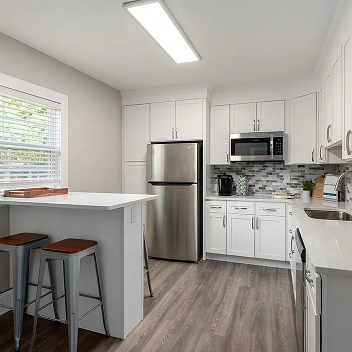 Bright and modern kitchen with white cabinets, stainless steel appliances, and wood flooring.