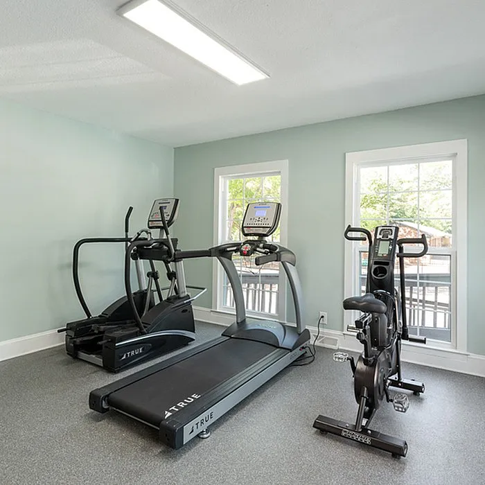 Modern home gym with treadmill, elliptical, and stationary bike in a well-lit space.