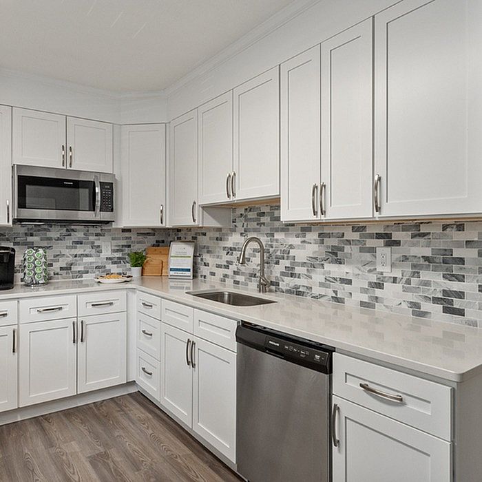 Modern kitchen with sleek white cabinets, stainless steel appliances, and a stylish backsplash.